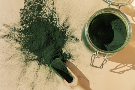 Organic blue-green algae spirulina powder food in glass jar with wooden spoon. Health benefits of spirulina chlorella. Vitamins and minerals to diet. Detox dietary supplement Seaweed superfoodの写真素材