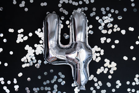 4 four metallic balloon with sparkling confetti on dark black background. Greeting card silver foil...