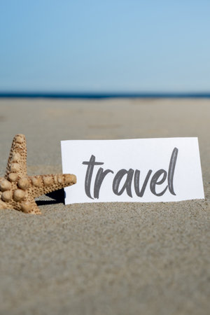 TRAVEL text on paper greeting card on background of starfish seashell summer vacation decor. Sandy beach sun coast. Holiday concept postcard. Getting away Travelの写真素材