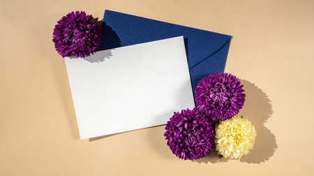 Composition with empty paper note and envelope beautiful spring violet and white flowers on beige...
