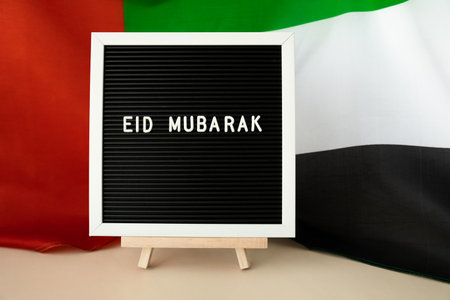Message text EID MUBARAK - happy holidays waving UAE flag on background concept. Greeting card...