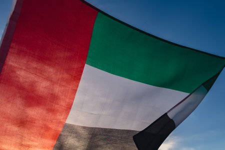 National Flag Of UAE Waving In The Wind sunset. Flag of United Arab Emirates on Sun Background. Sign...