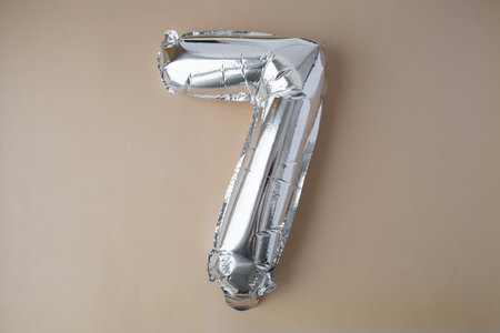 7 seven metallic balloon on beige neutral background. Greeting card silver foil balloon number Happy...