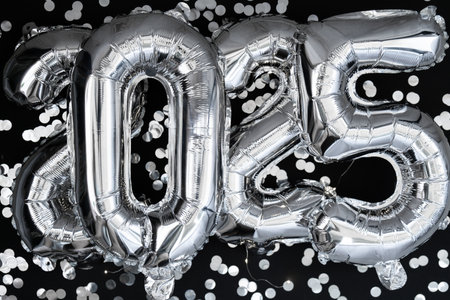 Happy new year 2025 metallic balloons with confetti on dark black background. Greeting card silver...