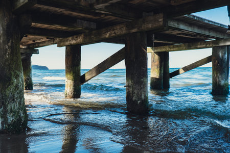 Storm sea waves under wooden pier in dramatic background wallpaper design. Seascape with running...