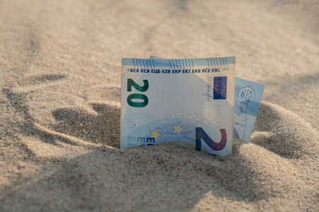 Money 20 euros bills in sandy beach. Concept finance saving money for holiday vacation. Costs in...