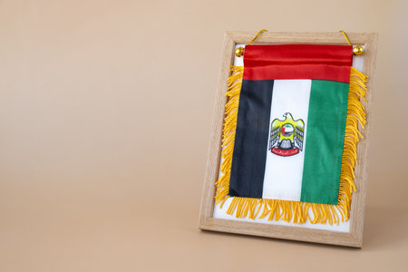 National symbol of UAE. United Arab Emirates small flag with Peregrine falcon on neutral beige...