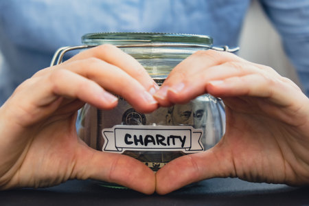 Female showing heart sign with hands Saving Money In Glass Jar filled with Dollars banknotes....