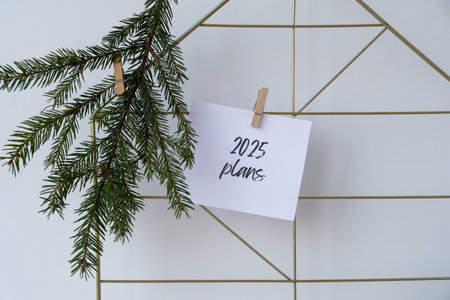 2025 PLANS text on white paper note on vision board with Christmas decor. New year aims resolutions....