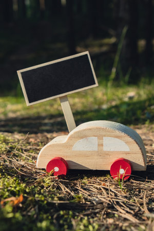 Empty blackboard with copy space Wooden toy car on greenery forest background. Eco-car concept World car free day electric vehicle environment automobile transportation electric vehicle. Hybrid electric. Sustainable engine. Zero CO2 emission for natural awarenessの写真素材