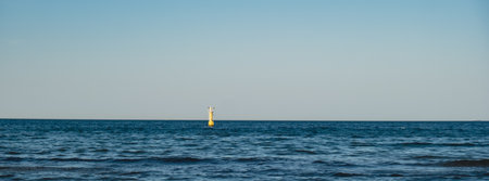 Yellow Lighthouse on blue sea line. Waves on sunny day on Baltic sea. Gdansk Poland.の写真素材