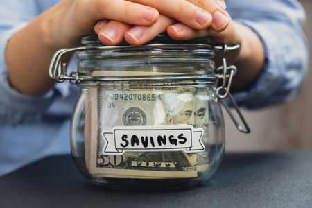 Unrecognizable woman holding Saving Money In Glass Jar filled with Dollars banknotes. SAVINGS...