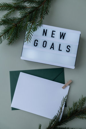 NEW GOALS text on Lightbox on green background with Christmas decor and copy space template mock up white envelope. New year aims resolutions. Planning and setting goalsの写真素材