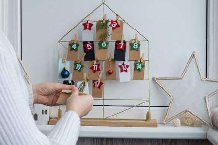 Number on craft paper notes with tasks before Christmas holidays. Female making kraft paper for handmade advent calendar Made with your own hands step by step DIYの写真素材