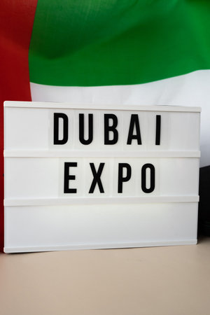 Lightbox with text DUBAI EXPO on background of waving UAE flag made from silk. United Arab Emirates...