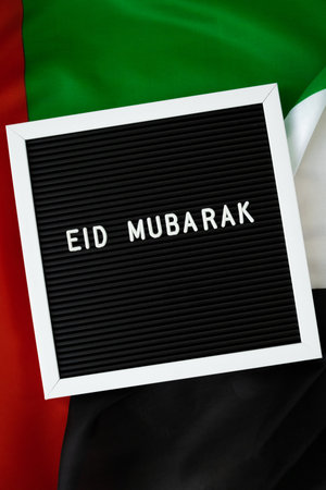 Message text EID MUBARAK - happy holidays waving UAE flag on background concept. Greeting card advertisement. Commemoration Day Muslim Ramadan Blessed holy month public holidayの写真素材