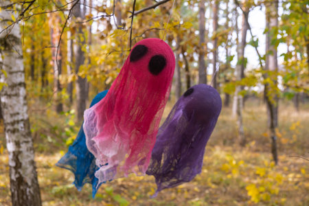 Trick or treat halloween colorful ghosts made of bandages flying in fall autumnal forest. Halloween greeting card. Handicraft handmade diyの写真素材