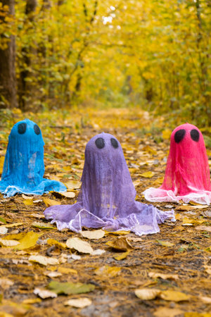 Halloween holiday concept. Handmade colorful ghosts made from bandages and glue in autumn forest background. Childrens art project. DIYの写真素材