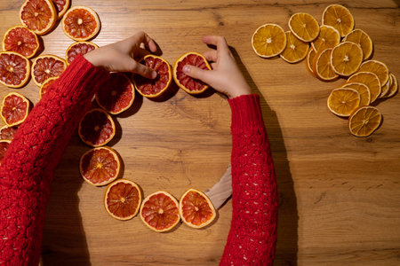 Step by step instruction of making handmade Christmas wreath made of dry fruits oranges and grapefruits. Female hands creating craft homemade decor. New year celebrationの写真素材