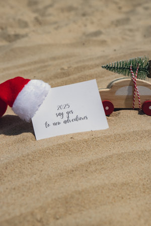 2025 SAY YES TO NEW ADVENTURES text on paper greeting card on background sandy beach sun coast. New...