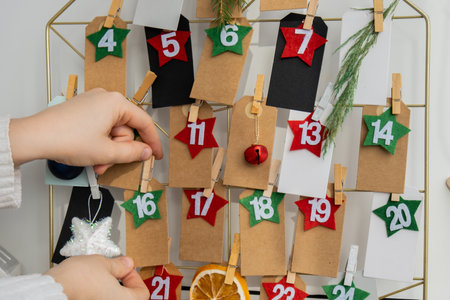 Number on craft paper notes with tasks before Christmas holidays. Female making kraft paper for handmade advent calendar Made with your own hands step by step DIYの写真素材