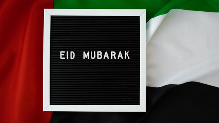 Message text EID MUBARAK - happy holidays waving UAE flag on background concept. Greeting card advertisement. Commemoration Day Muslim Ramadan Blessed holy month public holidayの写真素材