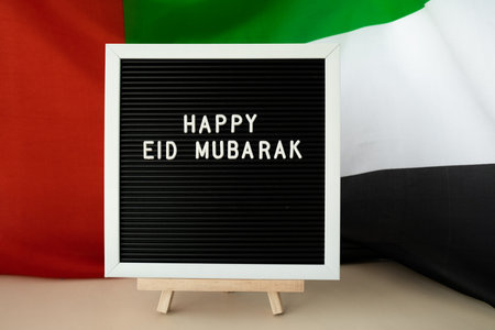 Congratulations with text HAPPY EID MUBARAK - happy holidays waving UAE flag on background concept....