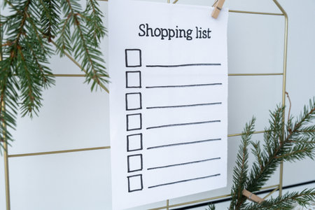 Holiday preparation paper note with SHOPPING LIST checklist text. Vision board wall with cozy minimalistic handmade new year Christmas decor Low key festive celebrationの写真素材