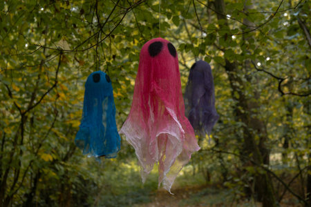 Halloween holiday concept. Handmade colorful ghosts made from bandages and glue flying in autumn forest background. Childrens art project. DIYの写真素材
