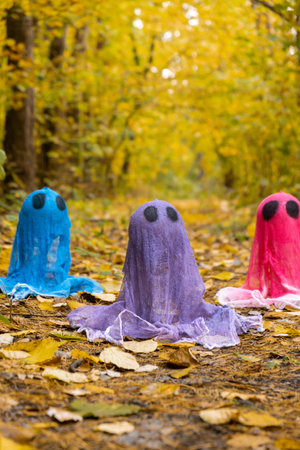 Trick or treat halloween colorful ghosts made of bandages in fall autumnal forest. Halloween greeting card. Handicraft handmade diyの写真素材