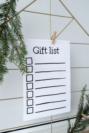Holiday preparation paper note with GIFT LIST checklist text. Vision board with cozy minimalistic handmade new year Christmas decor Low key festive celebrationの写真素材