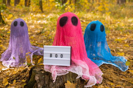 Trick or treat halloween colorful ghosts made of bandages in fall autumnal forest. Halloween greeting card. Handicraft handmade diyの写真素材