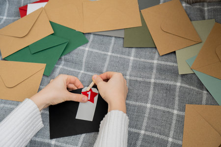 Number on craft envelopes notes with tasks before Christmas holidays. Female making kraft paper for handmade advent calendar Made with your own hands step by step DIYの写真素材