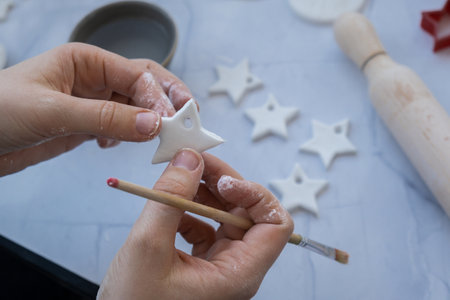 Christmas star Creator is using white air dry clay for making decor to Christmas tree holiday. Creating hobby recreation activity that involves fingers. DIY craftingの写真素材