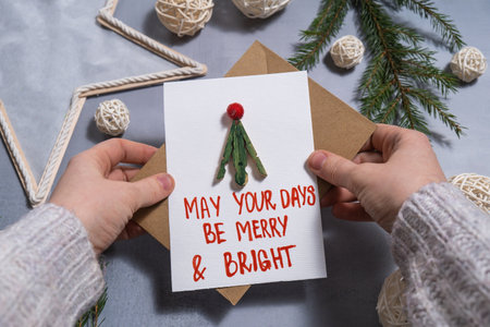 Christmas tree Sustainable Christmas preparation female hand holding handmade greeting cards with envelope. Inclusive and responsible holiday. Conscious celebrationの写真素材