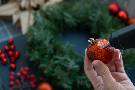 Crafter using hot glue DIY process of woman making Christmas arrangement with decor in red color. Small business, self employed entrepreneur, self-made career. Series of handmade craft instructions. Zero waste eco-friendly winter holiday decoration. New yearの写真素材