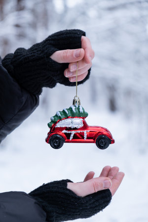 Female hands holding Christmas decoration outdoor in snowy winter forest. Postcard greeting card mock up. Holiday car toy branch Ornaments New Year celebrationの写真素材