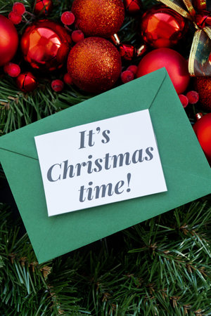 Christmas handmade wreath made of festive decorations with green envelope and paper note with ITS CHRISTMAS TIME text. Winter holiday celebration greeting cardの写真素材
