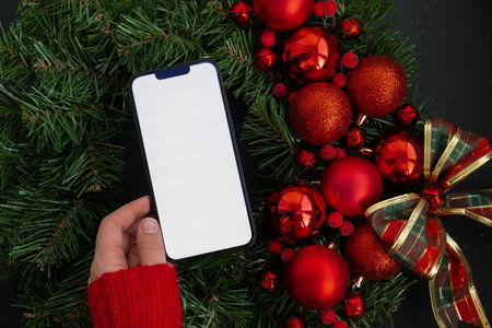 Smartphone mock up template white screen on handmade Christmas wreath. Zero waste eco-friendly Christmas. Sustainable greeting cardの写真素材