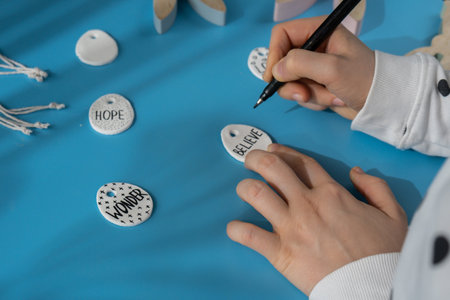 Workshop writing word BELIEVE on EASTER clay egg Creator is using white air dry clay for making decor to EASTER holiday. Creating hobby recreation activity that involves fingers. DIY craftingの写真素材