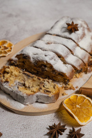 Slices of Christmas Stollen in Christmas lights and decoration. Traditional sweet fruit loaf with icing sugar festive pastry dessert. Holiday baking foodの写真素材