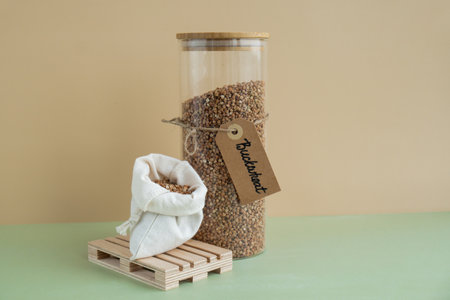Refillable glass jar with raw buckwheat porridge and cotton bag. Copy space Refill product format eco-friendly living. Filling reusable container Whole spelt grain species. High protein fiber-rich vegan plant based food ingredient. Gluten free superfood healthy nutritional dietaryの写真素材