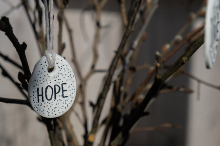Clay Easter eggs with words RISEN HOPE BELIEVE PEACE LOVE WONDER on wooden twig. Children air dry clay activity handicraft idea. Preparing for Easter holiday decorating. Modern organic design minimalistic plastic free sustainableの写真素材