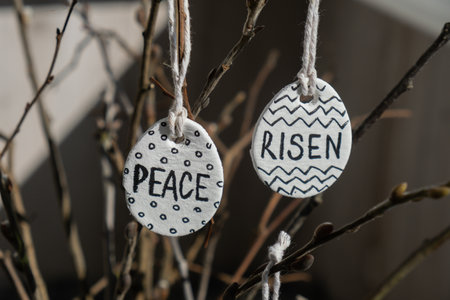 Clay Easter eggs with words RISEN HOPE BELIEVE PEACE LOVE WONDER on wooden twig. Children air dry clay activity handicraft idea. Preparing for Easter holiday decorating. Modern organic design minimalistic plastic free sustainableの写真素材