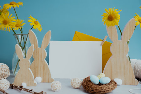 White empty envelope Postcard copy space traditional greeting card to christian holiday. Festive mood composition with bunnies eggs and yellow flowers on pastel blue background. Sustainable natural materialsの写真素材