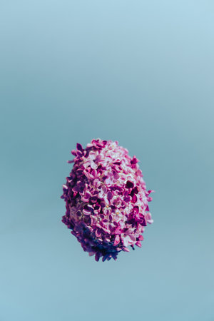 Easter egg made of lilac spring flowers levitating in pastel blue background. Sustainable holiday minimalistic still life composition. Copy space template for invitation greeting cardの写真素材