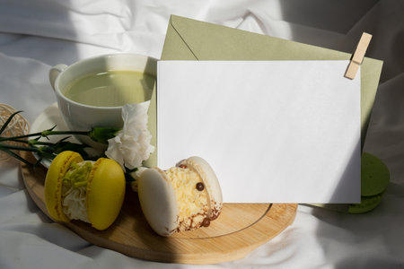 White paper letter copy space template Sweet yellow macaron dessert Cup of green plant based matcha tea latte in cozy morning bed atmosphere. Creative holiday romantic date idea. Herbal prebiotic fiber superfood beverage antioxidant-rich immunity-boostingの写真素材