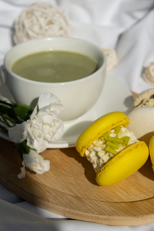 Green latte matcha with yellow and white sweet macaron. Concept of holiday breakfast morning tea drink. Cozy minimalist superfood vibrant colors healthy eating. Organic caffeine-freeの写真素材