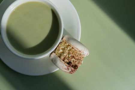 Green latte matcha with white cacao macaron dessert on pastel background with creative deep shadows....