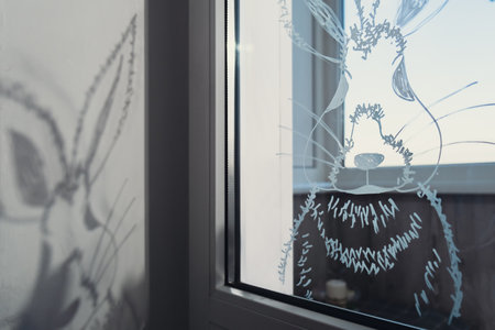 Zero cost responsible holiday decor economically driven. Painted Easter bunny rabbit on window glass indoor at home. Affordable alternative Easter springtime seasonal tradition ideas decorationの写真素材